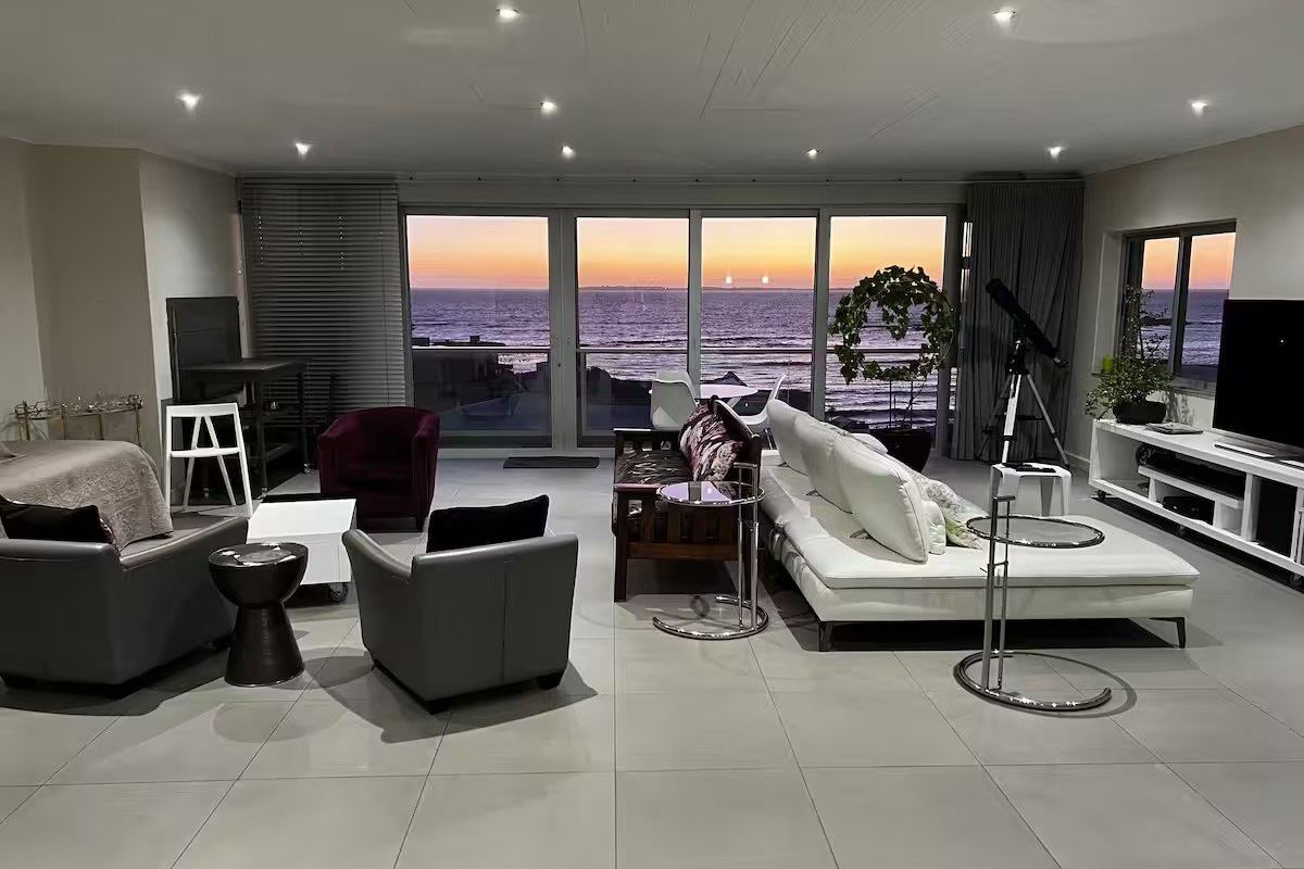 Spacious living area featuring large format floor tiles, recessed lighting, and expansive sliding glass doors offering panoramic ocean views.