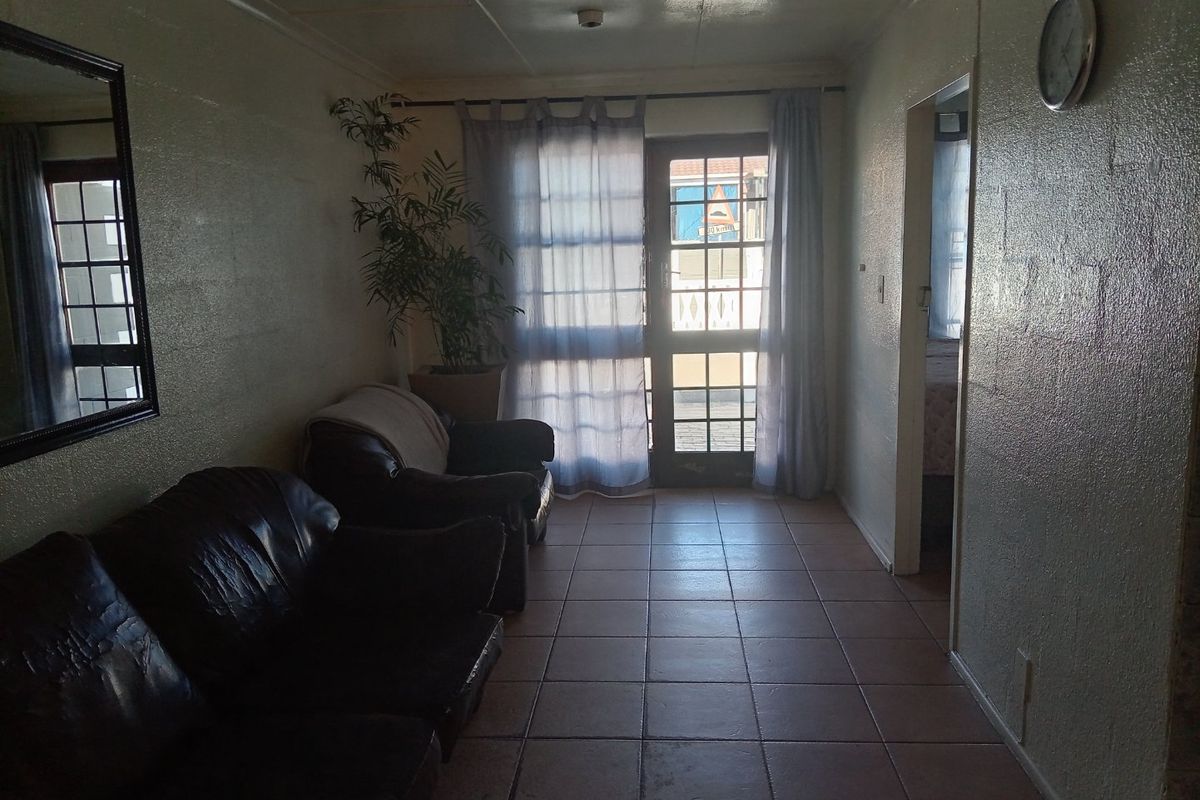A living area featuring tiled flooring and a glass-panelled door providing access to the exterior.