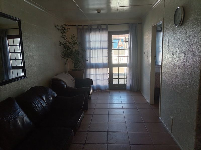 A living area featuring tiled flooring and a glass-panelled door providing access to the exterior.