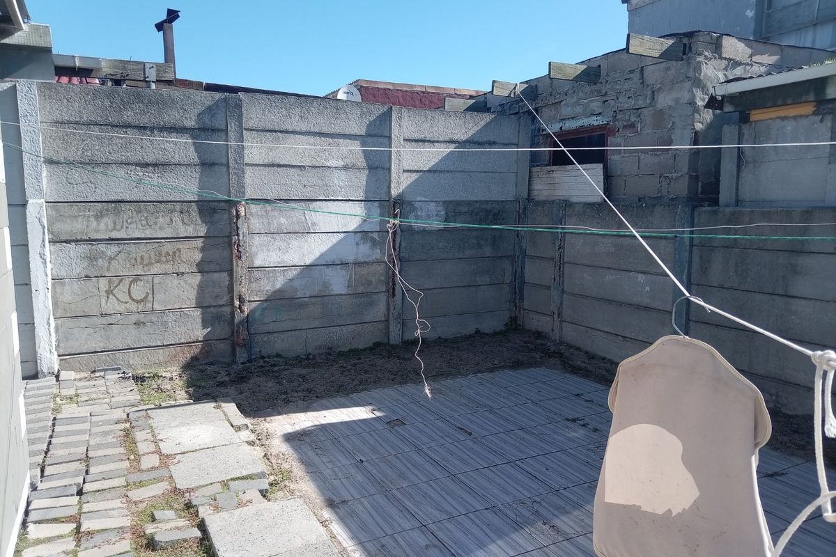 A rear outdoor area featuring a paved patio and precast concrete boundary walls, currently requiring maintenance and cosmetic improvements.