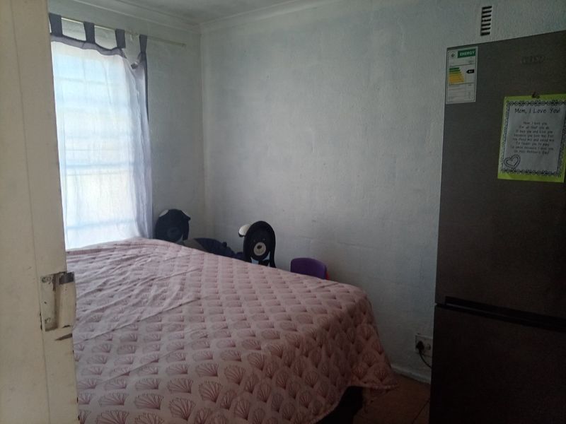 A compact bedroom featuring basic finishes, a window with curtains, and standard electrical infrastructure.