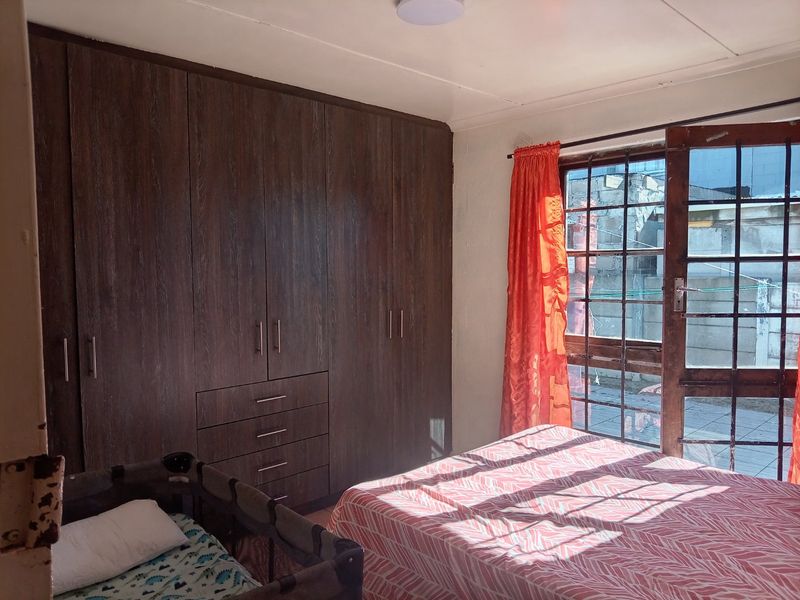 A bedroom featuring dark wood-finish built-in cupboards and a timber-framed glass door providing access to the exterior.