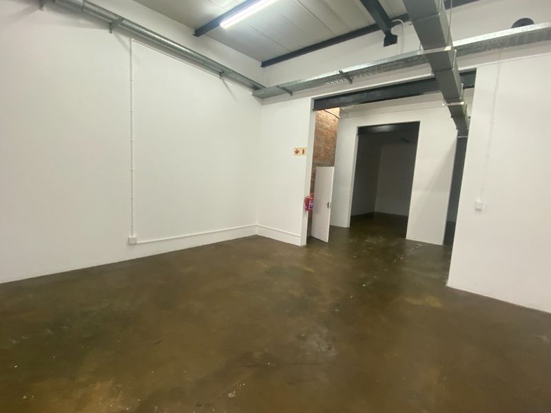 An open-plan industrial utility space featuring exposed ductwork, steel beams, and durable concrete flooring, suitable for storage or workshop use.