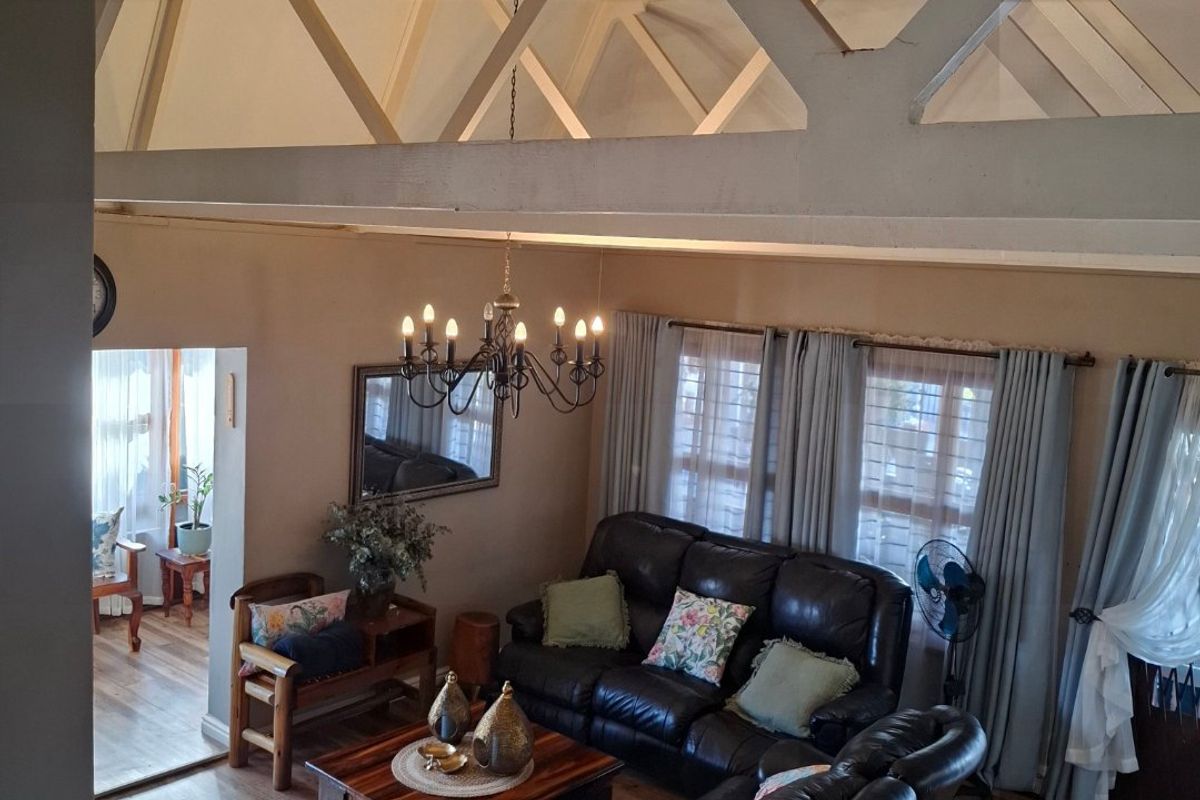 Spacious living room featuring high vaulted ceilings with exposed structural trusses, laminate flooring, and abundant natural light.
