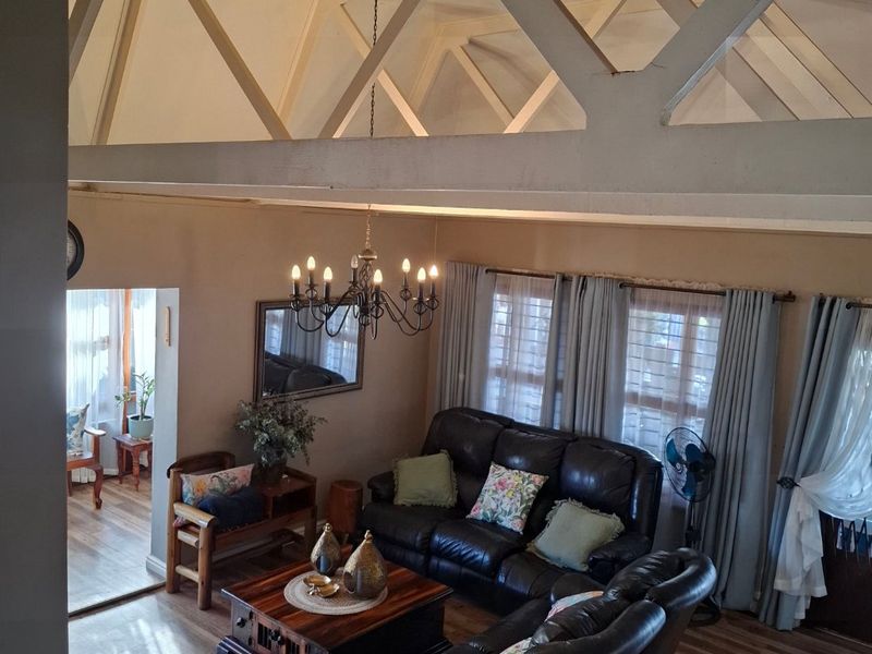 Spacious living room featuring high vaulted ceilings with exposed structural trusses, laminate flooring, and abundant natural light.