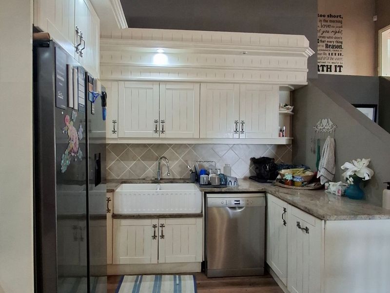 A well-appointed kitchen featuring classic shaker-style cabinetry, a farmhouse sink, stone countertops, and a high vaulted ceiling with modern finishes.