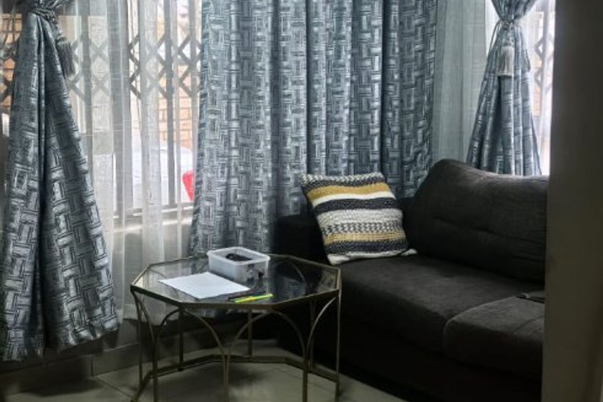 A living room featuring tiled flooring, a ceiling light fixture, and a security gate on the window.