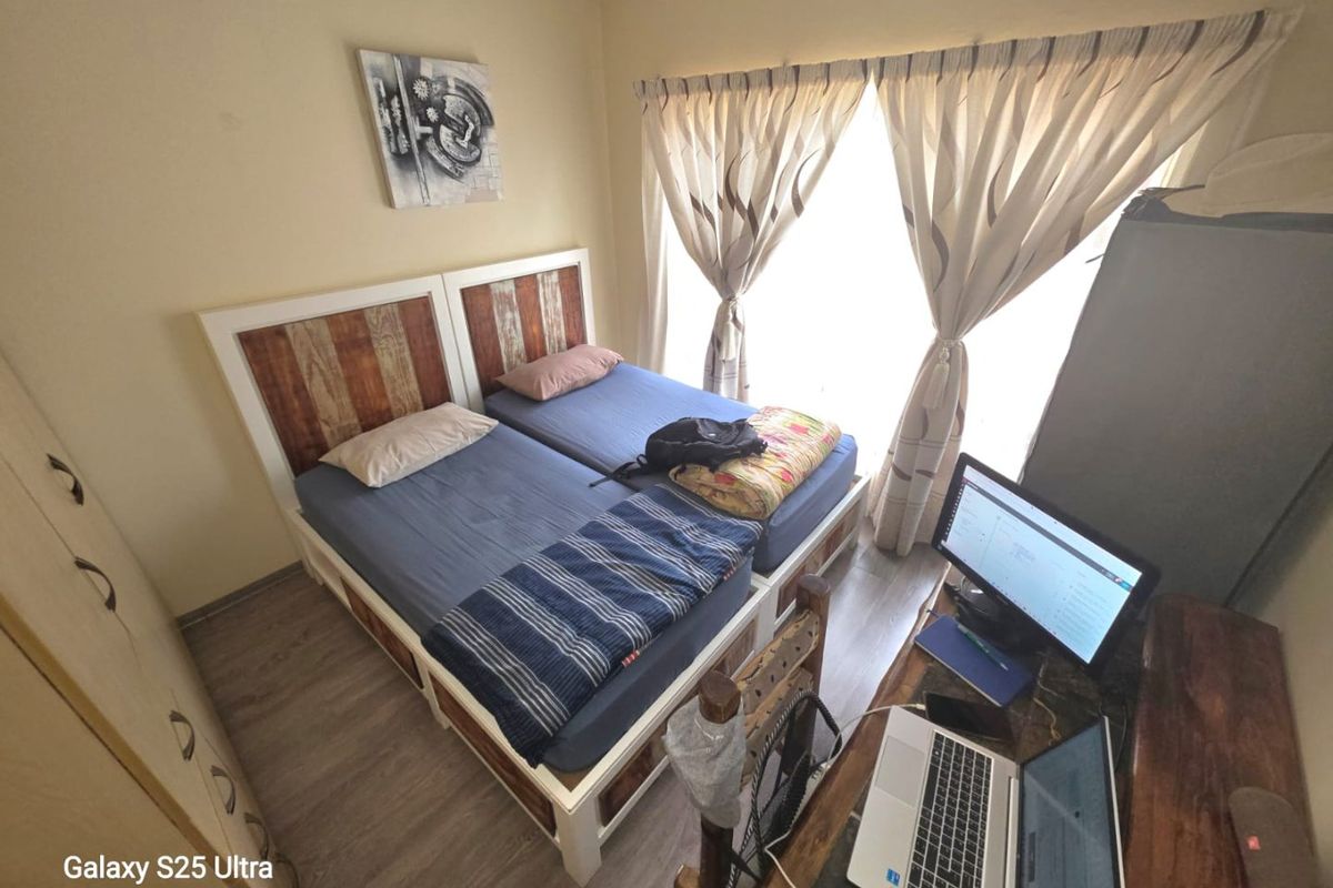 A functional bedroom featuring laminate flooring and a built-in wardrobe, offering a practical layout with natural light through the window.