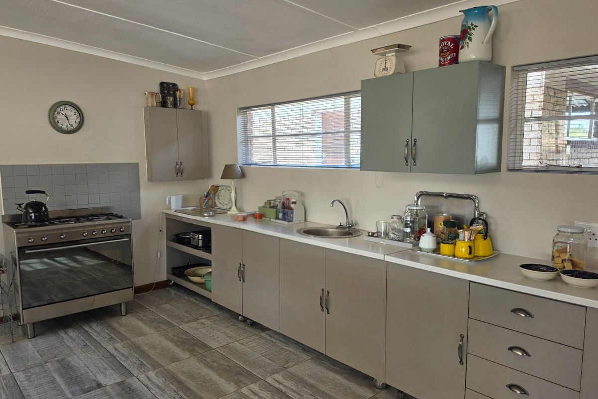 A functional kitchen featuring built-in cabinetry, a gas stove with oven, stainless steel sink, and tiled flooring.