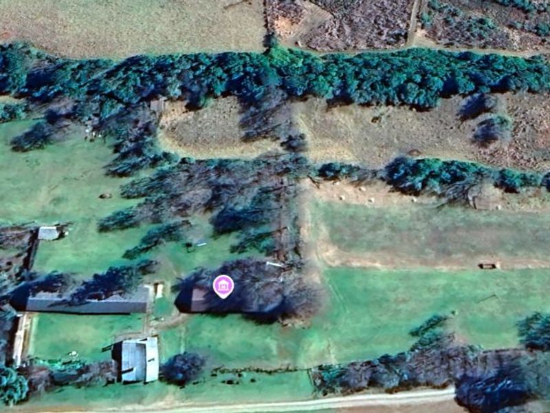 An aerial view of the farm property showing the layout of the land, existing outbuildings, and surrounding vegetation.