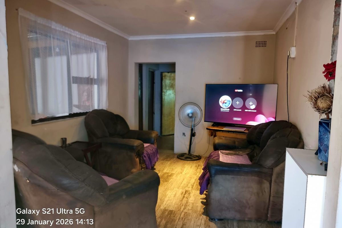 A living room featuring laminate flooring and recessed downlighting, requiring cosmetic updates to the wall finishes to improve the overall aesthetic.