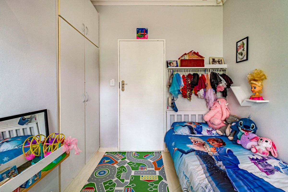 A functional bedroom featuring a built-in wardrobe and standard internal door, currently utilized as a child's room.