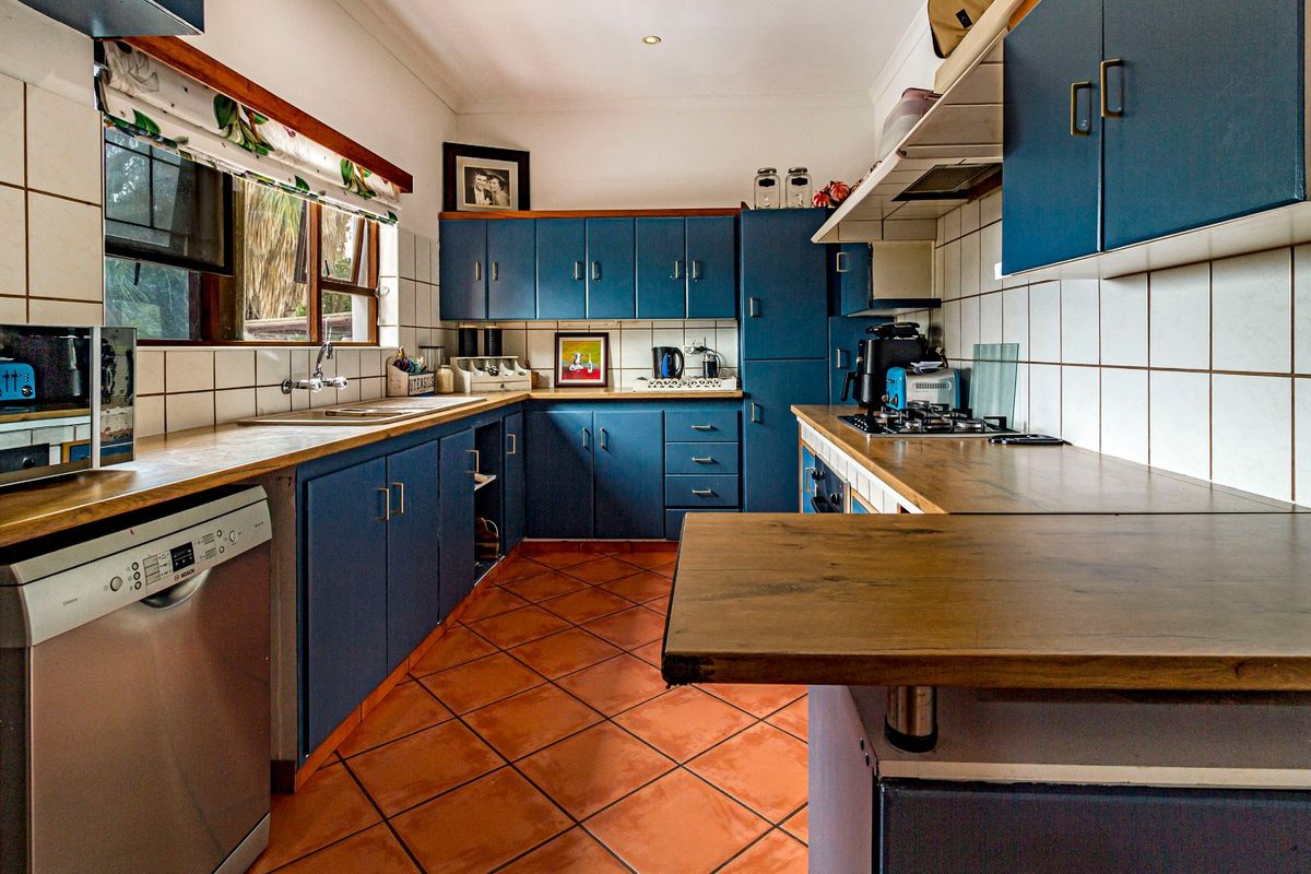 A functional kitchen featuring blue cabinetry, wood-look laminate countertops, a gas hob, and tiled flooring, offering a solid foundation for a modern update.
