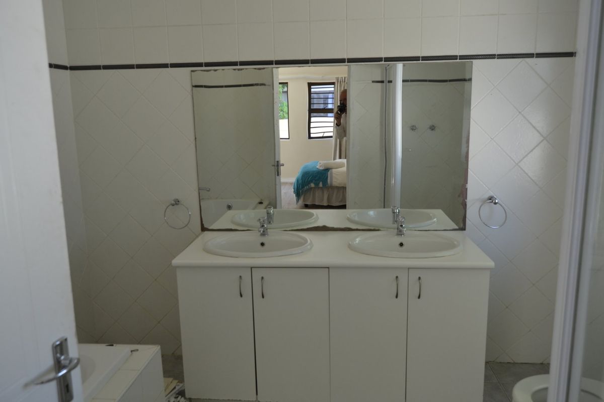 A functional bathroom featuring a double vanity with dual basins, wall-mounted mirrors, and tiled wall finishes.