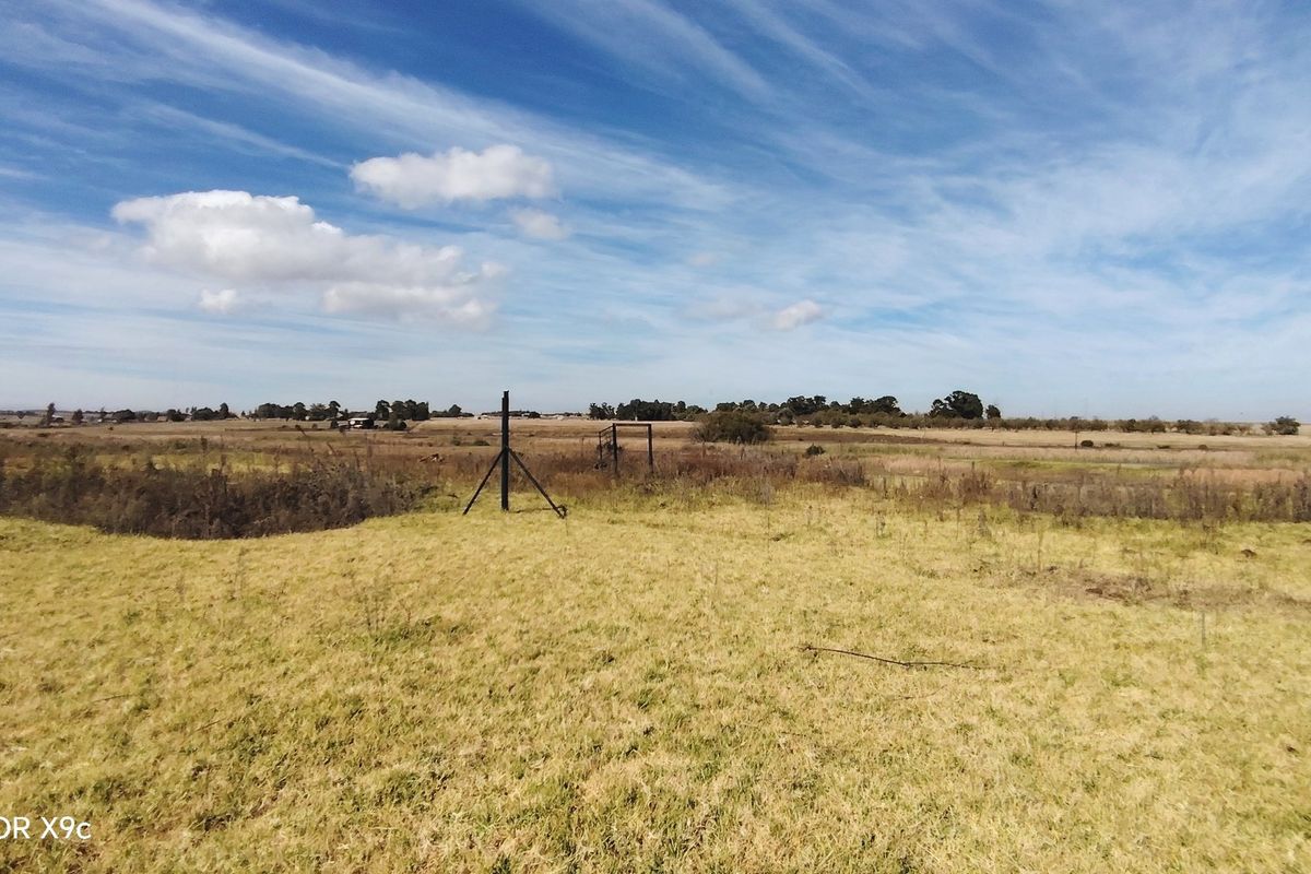 An expansive view of open, undeveloped land with natural grass and minimal fencing infrastructure.