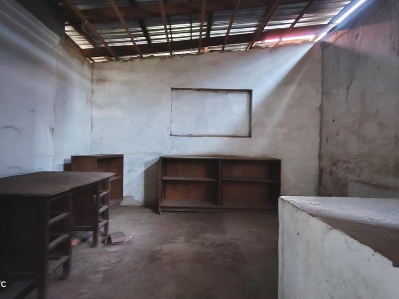 An unfinished interior space featuring exposed roof rafters, concrete flooring, and basic wall structures, requiring significant renovation and finishing work.
