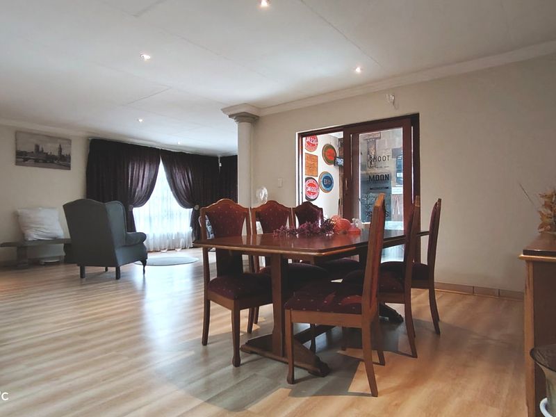 Spacious open-plan living and dining area featuring laminate flooring, recessed lighting, and a sliding glass door providing access to the exterior.