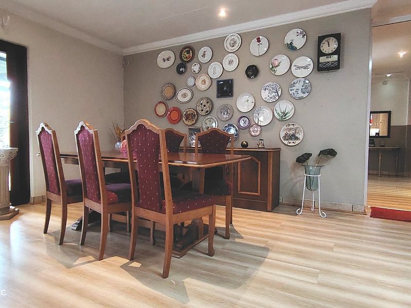 A dining room featuring light-toned laminate flooring, recessed lighting, and a sliding glass door providing natural light.