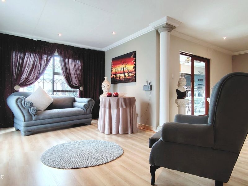 A well-maintained living area featuring light laminate flooring, a decorative structural column, and sliding glass doors providing access to the outdoor space.