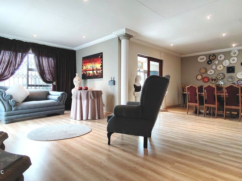 Spacious open-plan living and dining area featuring laminate flooring, recessed lighting, and a decorative column, creating a versatile and inviting living space.