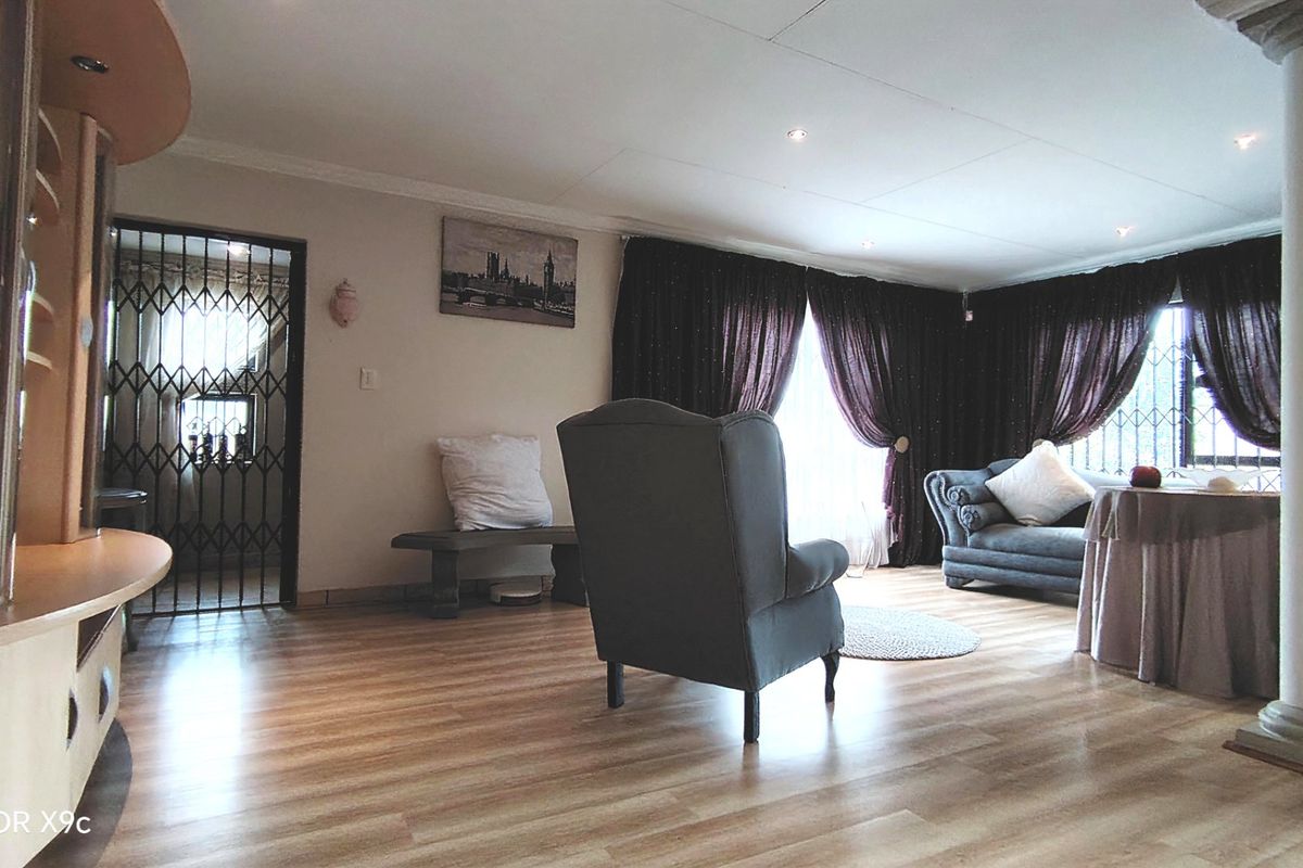 Spacious living room featuring laminate flooring, recessed downlighting, and a decorative column, providing a comfortable and functional lounge area.