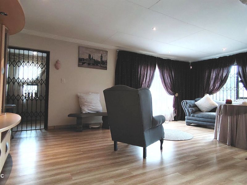 Spacious living room featuring laminate flooring, recessed downlighting, and a decorative column, providing a comfortable and functional lounge area.