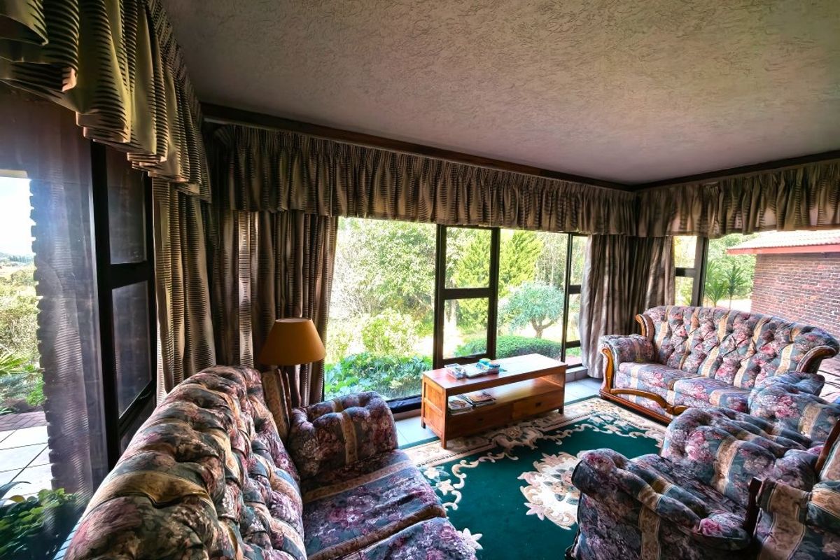 A spacious living room featuring large windows that provide ample natural light and views of the surrounding garden.
