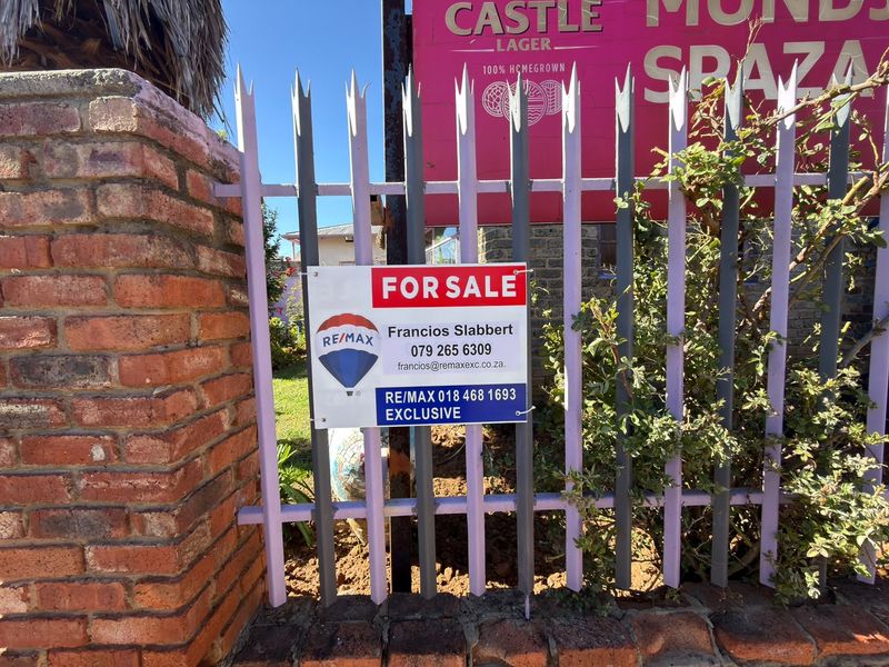 Front view of the property featuring a brick boundary wall and metal palisade fencing, currently listed for sale.