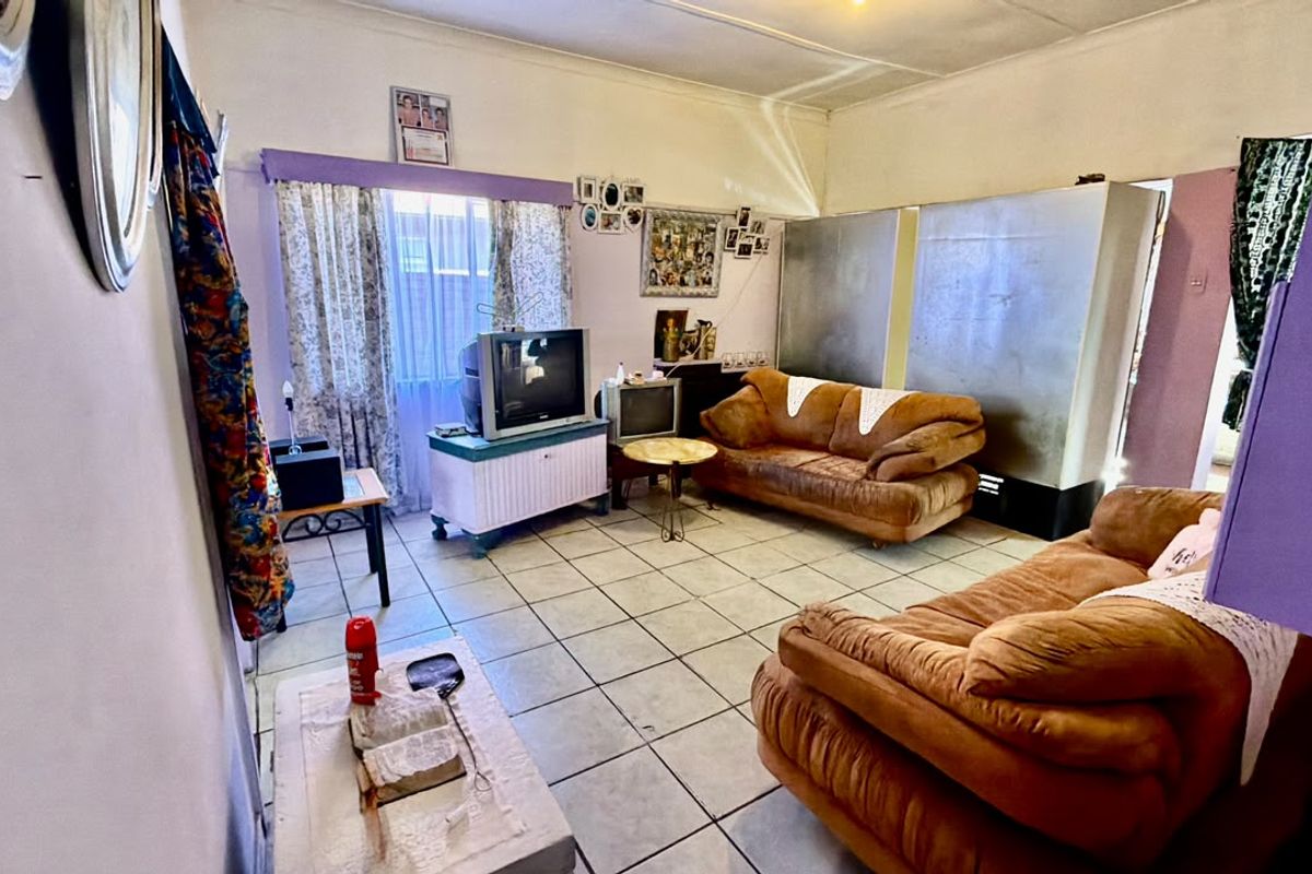 A living room featuring ceramic floor tiles and coved ceilings, currently requiring cosmetic updates and maintenance to improve the overall aesthetic.