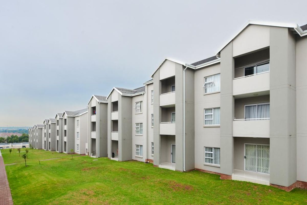 A view of the rear elevation of a multi-story apartment complex featuring private balconies, sliding doors, and well-maintained exterior finishes.