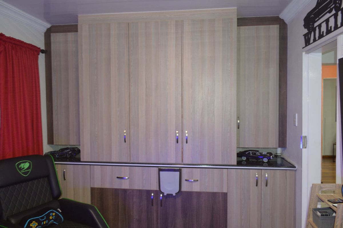 A bedroom featuring extensive built-in cabinetry with a modern wood-grain finish and a dark stone countertop, providing ample storage and workspace.