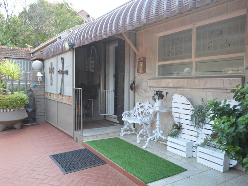 A covered patio area featuring brick paving, tiled flooring, and a metal awning, providing a functional outdoor space for relaxation.