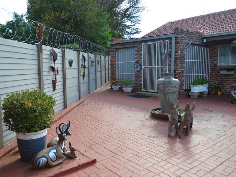 A paved rear courtyard area featuring a brick-built structure with security gates and a perimeter wall topped with razor wire.