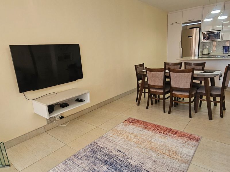 Open plan living and dining area featuring tiled floors and a modern kitchen with built-in cabinetry and island.