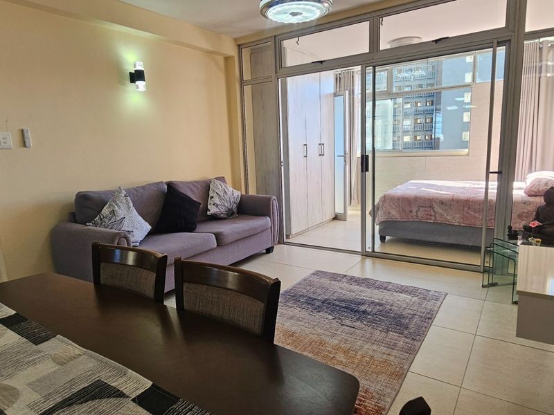 Open-plan living area featuring tiled flooring and large sliding glass doors that provide access to an adjoining bedroom space.