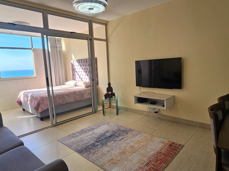 Open plan living area featuring tiled floors and large sliding glass doors that provide access to an adjoining bedroom space with ocean views.
