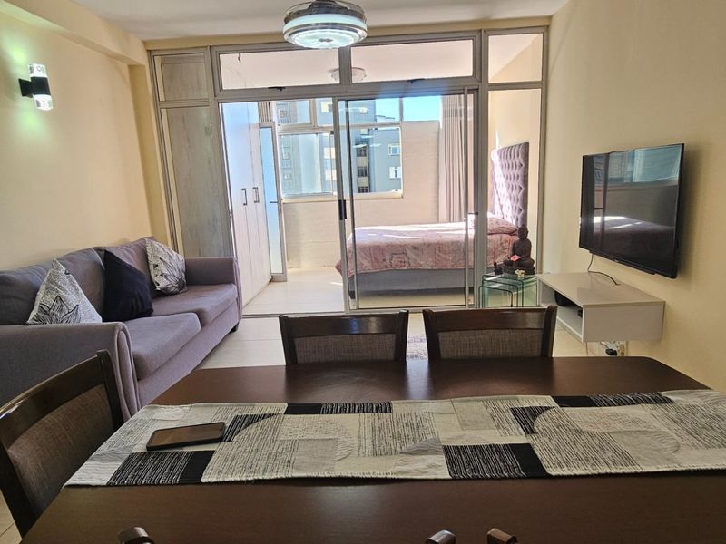 Open-plan living and dining area featuring tiled flooring and sliding glass doors leading to an adjacent bedroom space.