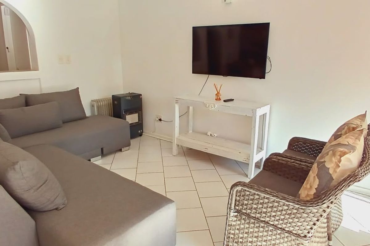 A bright living room featuring tiled flooring and a distinctive arched doorway leading to an adjacent space.