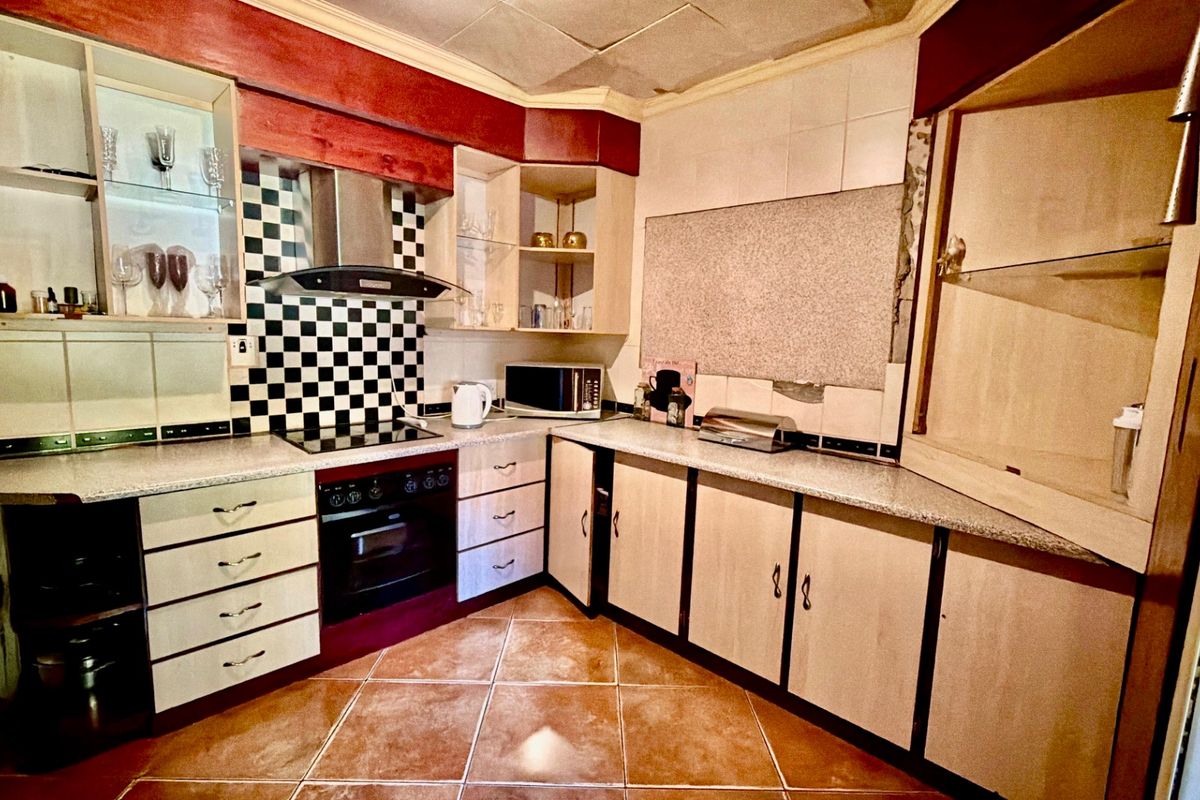 A dated kitchen featuring built-in cabinetry, a tiled backsplash, and integrated appliances, requiring cosmetic updates to modernize the space.