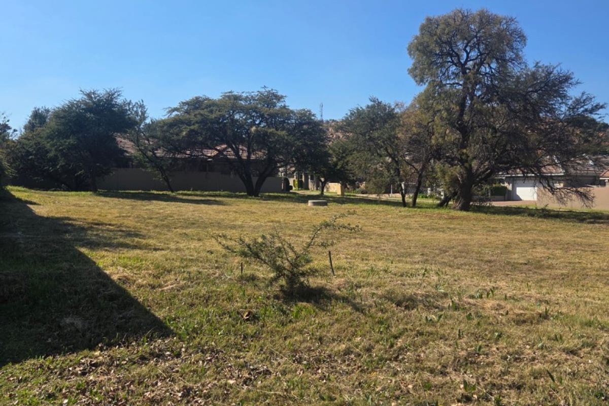 A spacious, open garden area featuring established mature trees and a grass lawn, offering potential for landscaping or outdoor development.