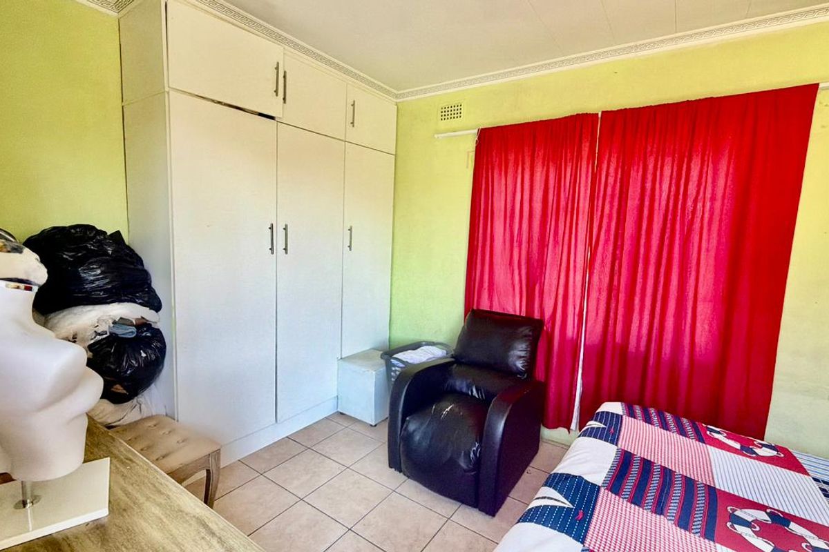 A bedroom featuring built-in cupboards, tiled flooring, and decorative cornice. The room requires cosmetic updates to the wall finishes.