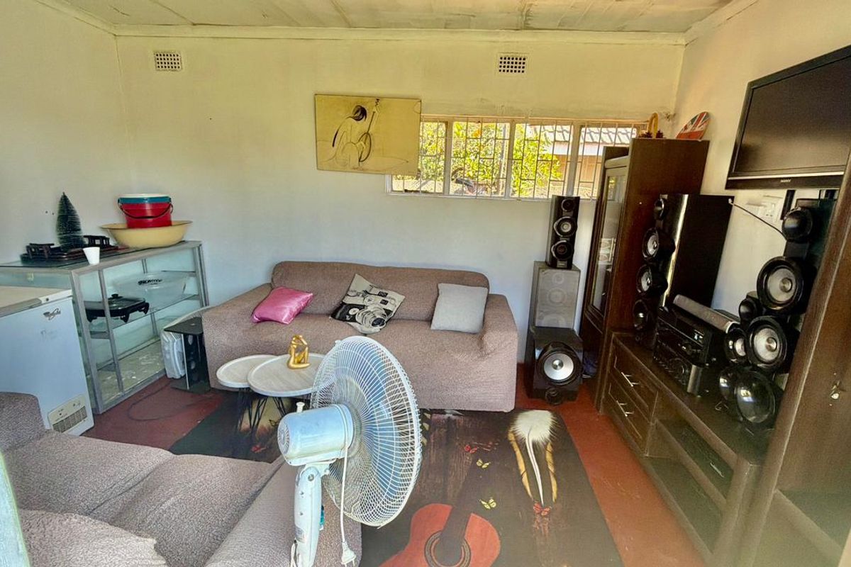 A living room featuring basic finishes, including burglar bars on the windows and ceiling ventilation grilles, requiring cosmetic updates to improve the overall condition.