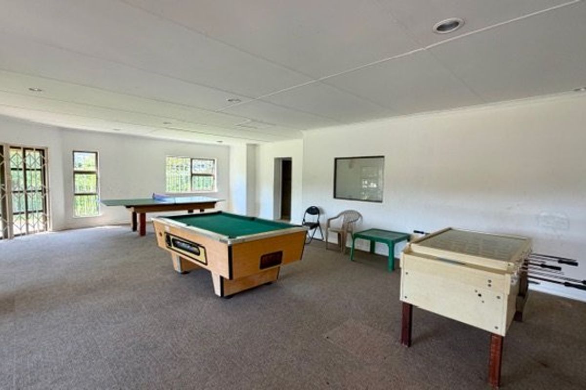 Spacious open-plan living area featuring carpet flooring, recessed downlights, and security-gated access to the exterior.