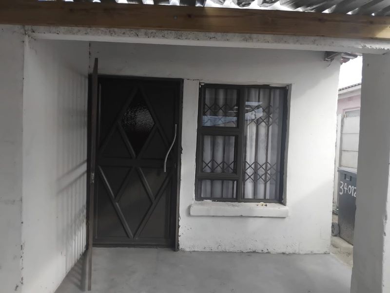 Front entrance area featuring a security door, window with security bars, and a covered concrete porch.