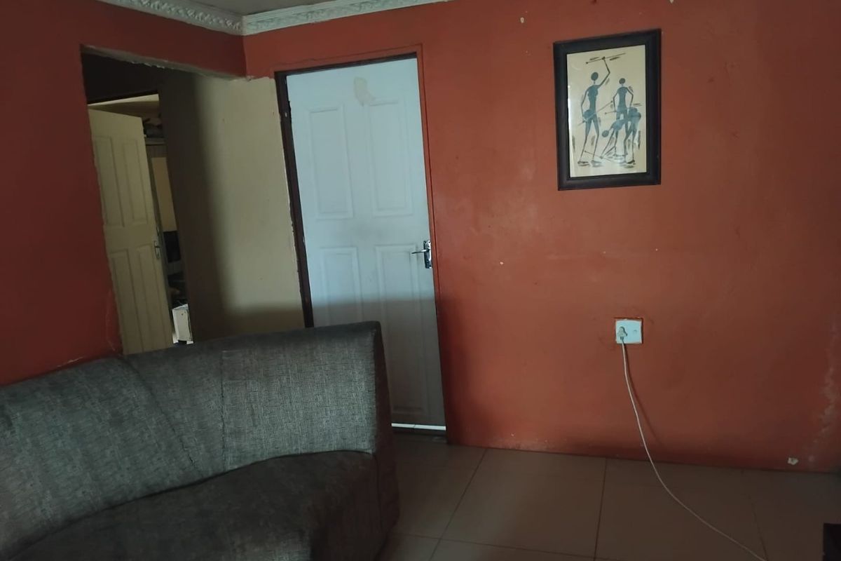 A living room area featuring tiled flooring and decorative ceiling cornicing, currently finished with bold wall paint.