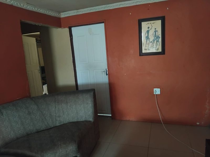 A living room area featuring tiled flooring and decorative ceiling cornicing, currently finished with bold wall paint.