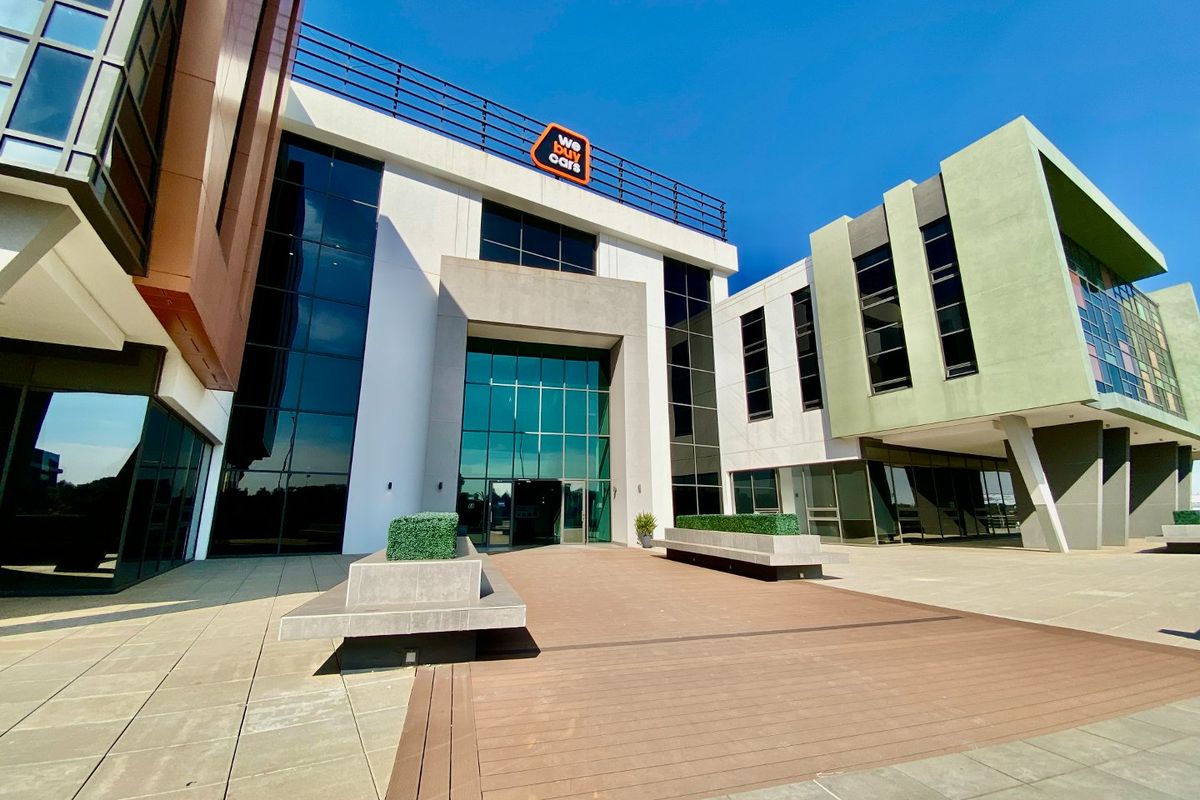 Modern commercial building entrance featuring a glass facade, composite decking, and integrated concrete planters in a well-maintained professional setting.
