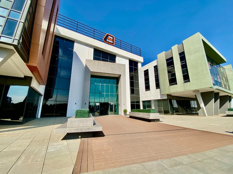Modern commercial building entrance featuring a glass facade, composite decking, and integrated concrete planters in a well-maintained professional setting.