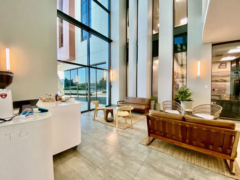 Modern commercial entrance lobby featuring double-volume ceilings, expansive floor-to-ceiling glass windows, and high-quality tiled flooring.