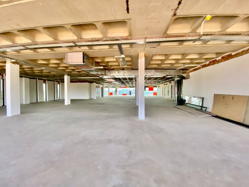 Expansive open-plan commercial office space featuring an exposed concrete waffle ceiling, structural columns, and industrial-style exposed HVAC ducting, currently in shell condition.